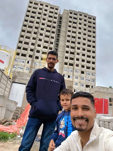 Kaliton e o filho em frente ao prédio em obra do futuro apartamento